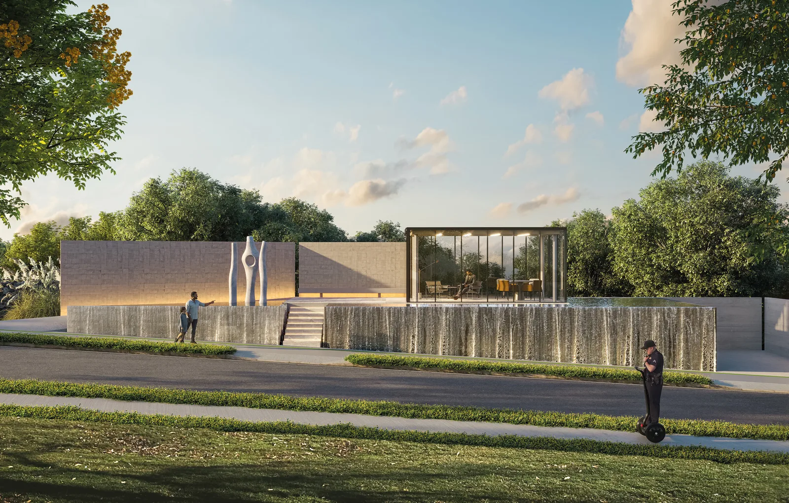 A Casa da Nascente ao entardecer: volume baixo de concreto e vidro sobre um muro de pedra, com esculturas verticais no pátio elevado, espelho d’água à frente e mata ao fundo.